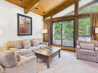Experience mountain living in this cozy living room featuring a plush sectional sofa and a comfortable armchair, perfect for relaxing after a day of adventure.