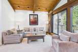Experience mountain living in this beautifully appointed living room, featuring a vaulted wood-beamed ceiling and a large picture window offering serene views.