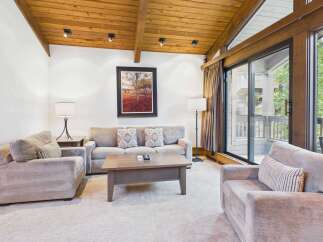 Experience mountain living in this beautifully appointed living room, featuring a vaulted wood-beamed ceiling and a large picture window offering serene views.