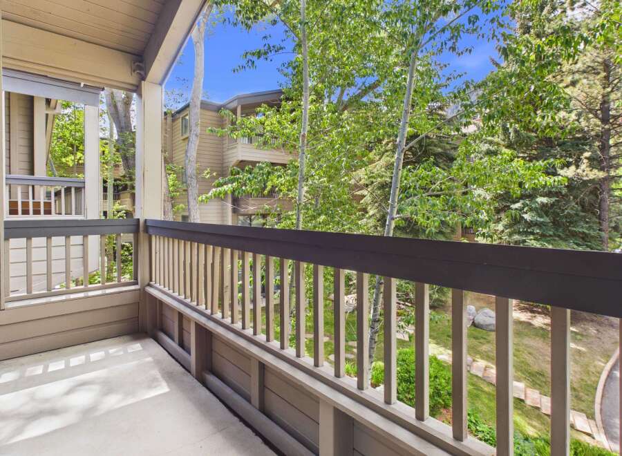 Enjoy the fresh mountain air from this charming balcony, offering serene views of lush greenery and surrounding architecture.