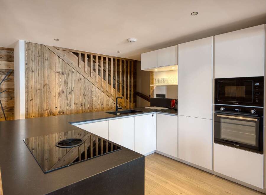 This stunning kitchen boasts a modern design with sleek white cabinetry and a contrasting black countertop.