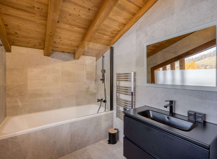 This luxurious bathroom boasts a stunning design with a wooden beamed ceiling, creating a warm and inviting atmosphere.