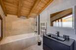 This luxurious bathroom boasts a stunning design with a wooden beamed ceiling, creating a warm and inviting atmosphere.