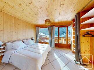 Experience the charm of this cozy bedroom, featuring warm wooden accents and a stunning view.