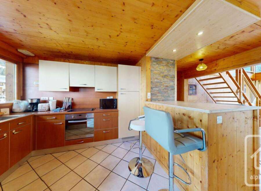 This charming kitchen boasts a warm, inviting atmosphere with its wooden ceiling and cabinetry.