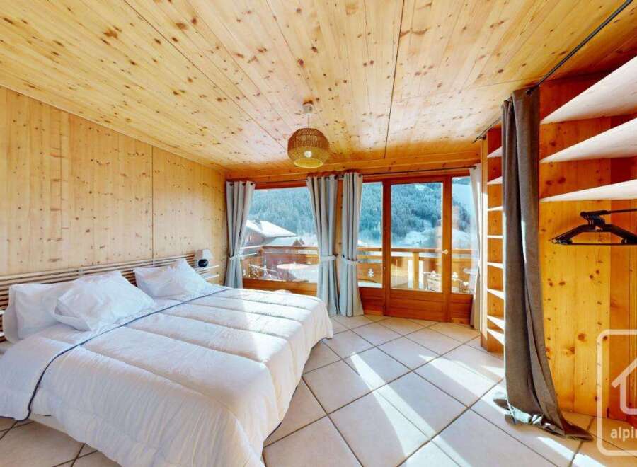 Experience the charm of this stunning bedroom, featuring a cozy wooden interior and a breathtaking mountain view.