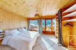 Experience the charm of this stunning bedroom, featuring a cozy wooden interior and a breathtaking mountain view.