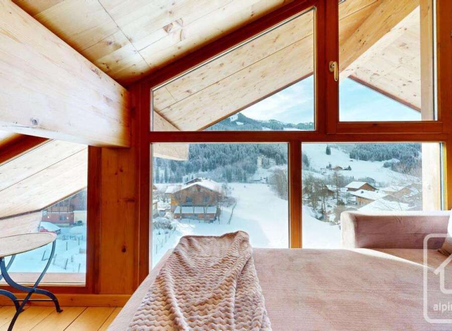Experience the charm of this alpine property, featuring stunning views of a snow-covered landscape through expansive windows.