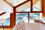 Experience the charm of this alpine property, featuring stunning views of a snow-covered landscape through expansive windows.