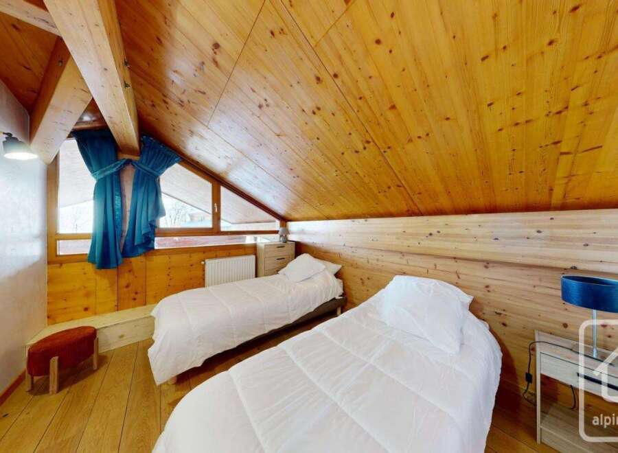 This charming bedroom features a cozy, wooden-paneled ceiling and walls, creating a warm and inviting atmosphere.