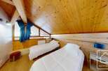 This charming bedroom features a cozy, wooden-paneled ceiling and walls, creating a warm and inviting atmosphere.