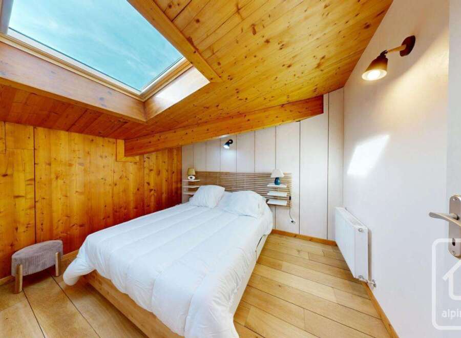 This charming bedroom features a cozy wooden ceiling and walls, creating a warm and inviting atmosphere.
