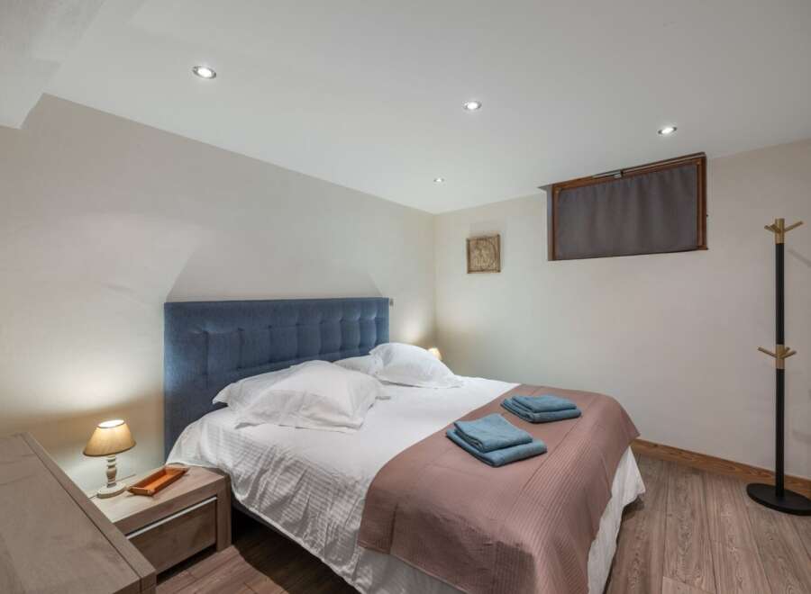 This cozy bedroom features a comfortable bed with a stylish blue headboard and soft bedding.