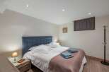 This cozy bedroom features a comfortable bed with a stylish blue headboard and soft bedding.