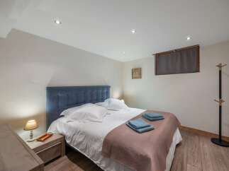 This cozy bedroom features a comfortable bed with a stylish blue headboard and soft bedding.