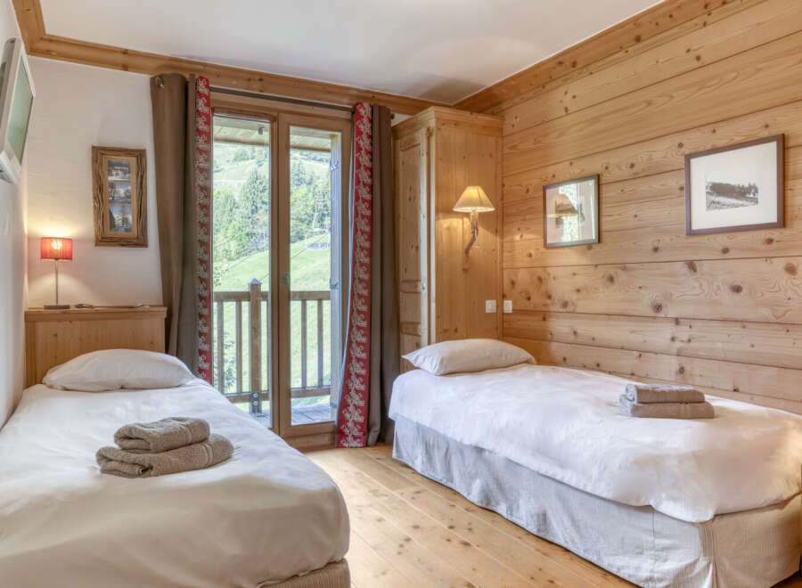This cozy bedroom features natural wood paneling and two twin beds, perfect for a comfortable stay.