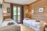 This cozy bedroom features natural wood paneling and two twin beds, perfect for a comfortable stay.
