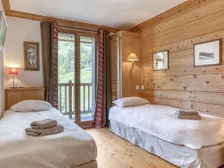 This cozy bedroom features natural wood paneling and two twin beds, perfect for a comfortable stay.