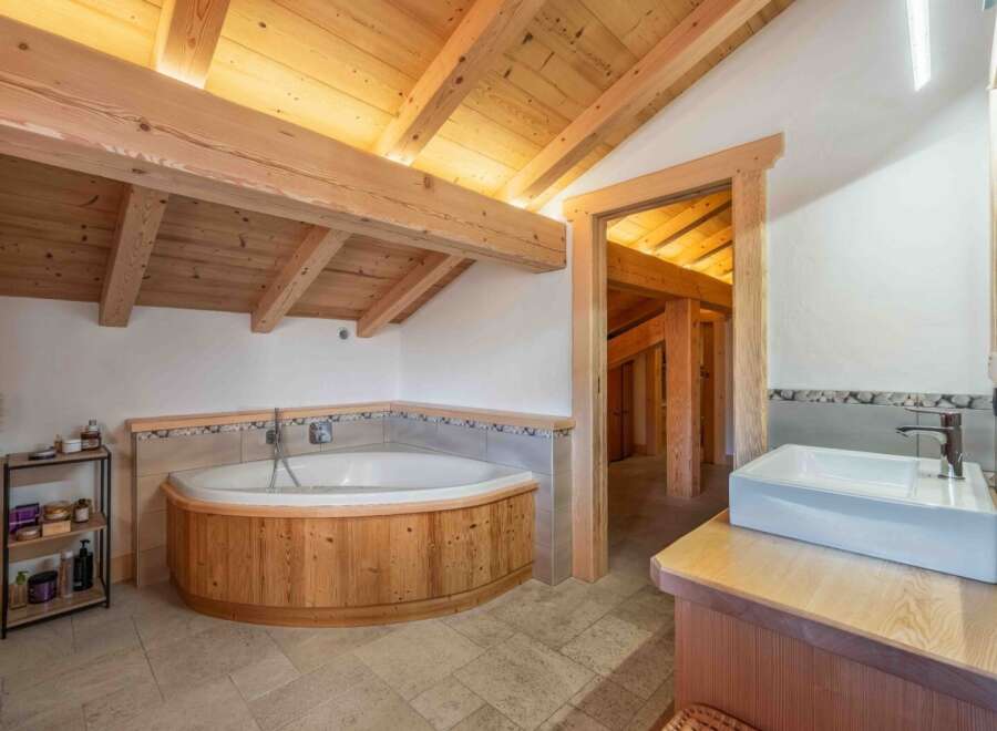 Experience luxury in this stunning bathroom featuring a unique wooden bathtub and a stylish sink area.