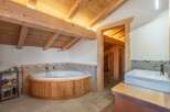 Experience luxury in this stunning bathroom featuring a unique wooden bathtub and a stylish sink area.