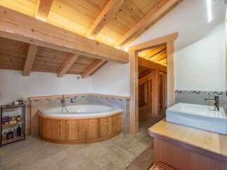 Experience luxury in this stunning bathroom featuring a unique wooden bathtub and a stylish sink area.