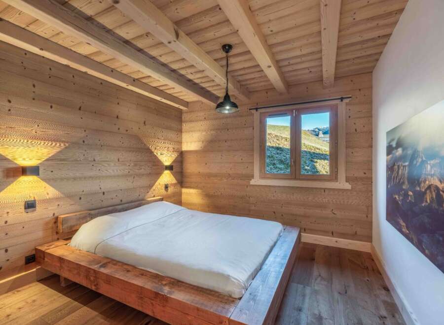 This stunning bedroom showcases a rustic design with wooden walls and ceiling, creating a warm and inviting atmosphere.
