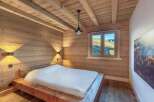 This stunning bedroom showcases a rustic design with wooden walls and ceiling, creating a warm and inviting atmosphere.