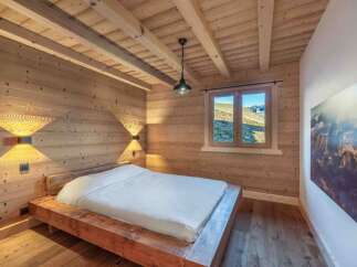 This stunning bedroom showcases a rustic design with wooden walls and ceiling, creating a warm and inviting atmosphere.