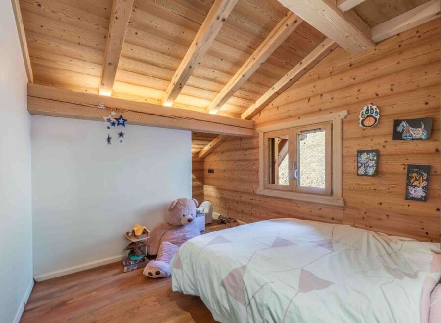 This charming bedroom features a cozy, rustic design with wooden walls and ceiling, creating a warm and inviting atmosphere.