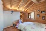 This charming bedroom features a cozy, rustic design with wooden walls and ceiling, creating a warm and inviting atmosphere.