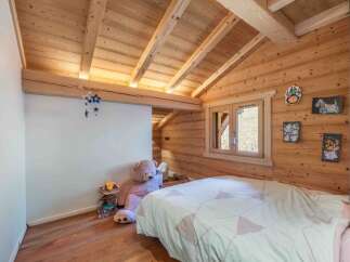 This charming bedroom features a cozy, rustic design with wooden walls and ceiling, creating a warm and inviting atmosphere.