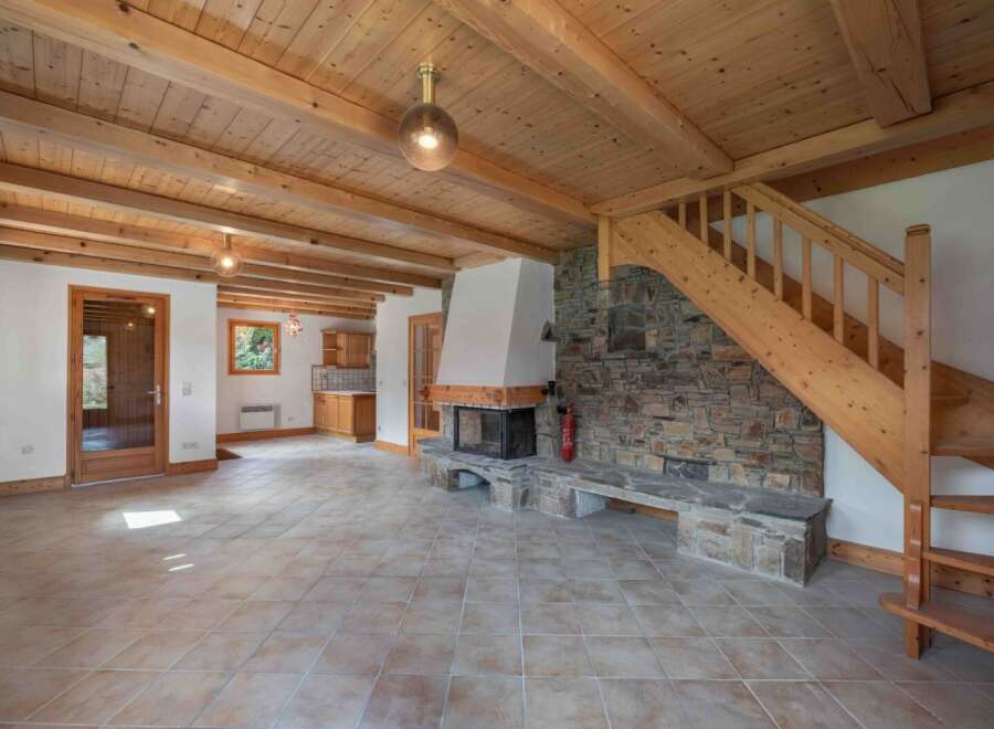 This stunning property boasts a warm and inviting interior, featuring a beautiful stone fireplace and exposed wooden beams.