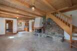 This stunning property boasts a warm and inviting interior, featuring a beautiful stone fireplace and exposed wooden beams.