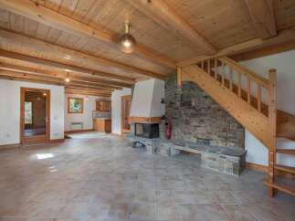 This stunning property boasts a warm and inviting interior, featuring a beautiful stone fireplace and exposed wooden beams.