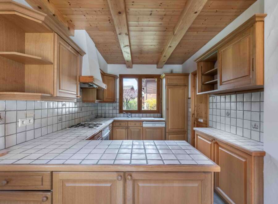 This charming kitchen boasts a warm, inviting atmosphere with its wooden cabinetry and tiled countertops.