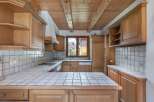 This charming kitchen boasts a warm, inviting atmosphere with its wooden cabinetry and tiled countertops.