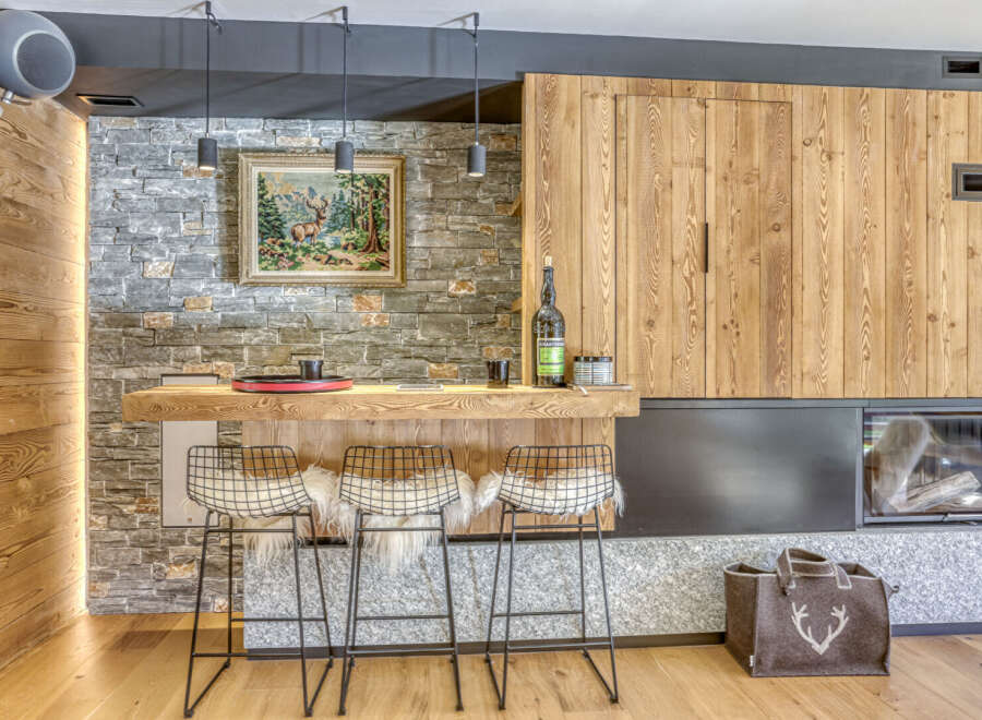 Experience rustic elegance in this stunning property, featuring a beautifully designed bar area with stylish wire chairs and a cozy fireplace.