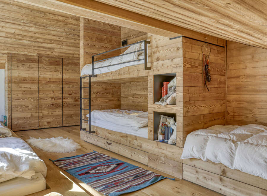 This cozy bedroom features custom-built bunk beds and a warm wooden interior, perfect for a mountain retreat.