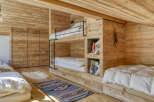 This cozy bedroom features custom-built bunk beds and a warm wooden interior, perfect for a mountain retreat.