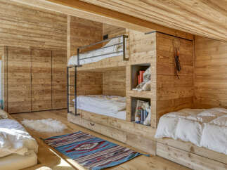This cozy bedroom features custom-built bunk beds and a warm wooden interior, perfect for a mountain retreat.
