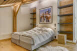 This cozy bedroom boasts a rustic charm with its wooden beams and paneling.