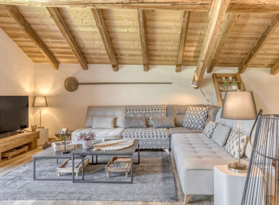 Experience rustic charm in this stunning living space, featuring exposed wooden beams and a cozy sectional sofa.