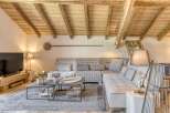 Experience rustic charm in this stunning living space, featuring exposed wooden beams and a cozy sectional sofa.