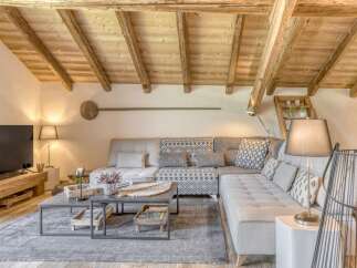 Experience rustic charm in this stunning living space, featuring exposed wooden beams and a cozy sectional sofa.