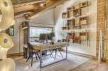 Discover the charm of this stunning home office, featuring a unique wooden desk and a custom-built bookshelf.