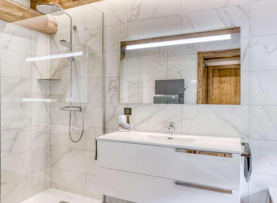 This modern bathroom features a sleek white vanity and a luxurious walk-in shower.