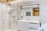 This modern bathroom features a sleek white vanity and a luxurious walk-in shower.