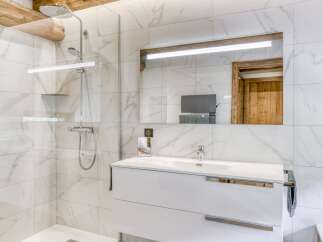 This modern bathroom features a sleek white vanity and a luxurious walk-in shower.