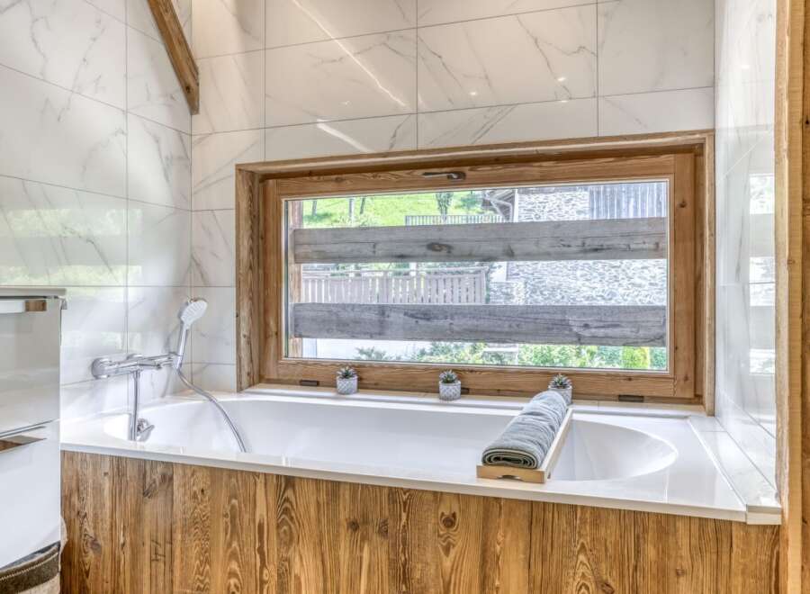 Experience luxury in this stunning bathroom featuring a modern bathtub and a serene view through the window.