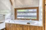 Experience luxury in this stunning bathroom featuring a modern bathtub and a serene view through the window.